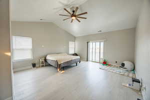 Bedroom with access to exterior, wood finished floors, a ceiling fan, and a high ceiling