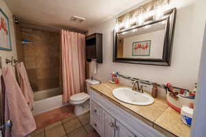 Full bathroom featuring vanity, shower / tub combo with curtain, dark tile patterned floors, a textured ceiling, and backsplash