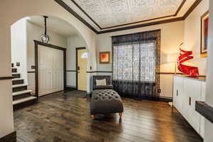 Sitting room featuring ornamental molding, an ornate ceiling, dark wood-type flooring, and arched walkways