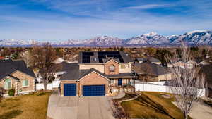 View of front of property featuring solar panels, covered porch, a mountain view, concrete driveway, and a residential view