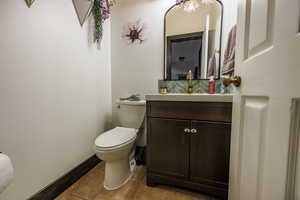 Half bath with vanity, decorative backsplash, and tile patterned floors