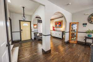 Foyer entrance with dark wood-style flooring and arched walkways