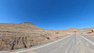 View of asphalt road featuring a mountain view and curbs