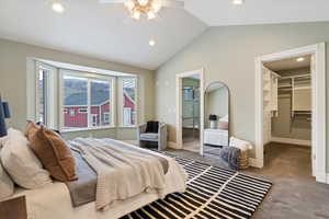 Carpeted bedroom with lofted ceiling, a walk in closet, recessed lighting, ensuite bath, and ceiling fan