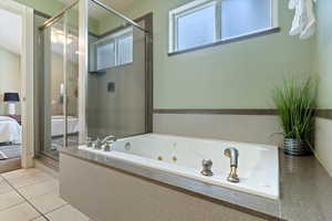 Full bathroom featuring a shower stall, a jetted tub, ensuite bath, and tile patterned flooring