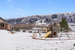 Snow covered playground with a playground and a mountain view