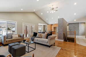 Living room featuring light wood-style floors, a high ceiling, french doors, ceiling fan, and plenty of natural light