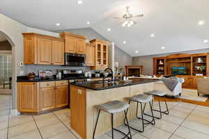 Kitchen with arched walkways, a kitchen breakfast bar, dark stone countertops, open floor plan, and stainless steel appliances