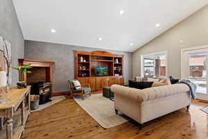 Living room featuring light wood-style floors, recessed lighting, a wood stove, and vaulted ceiling