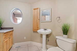 Half bathroom with toilet and light tile patterned flooring