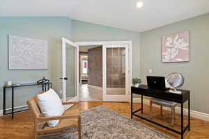 Home office with french doors, light wood-style floors, and lofted ceiling