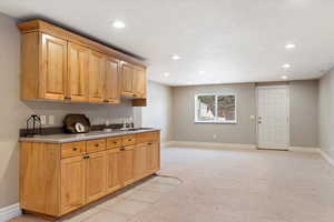 Kitchen featuring light carpet, light countertops, recessed lighting, light tile patterned floors, and light wood finish cabinets