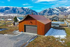Snow covered garage featuring a mountain view, a garage, and gravel driveway