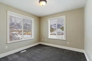 Unfurnished room featuring baseboards and dark colored carpet