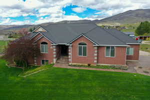 Single story home featuring a mountain view, brick siding, and a front lawn
