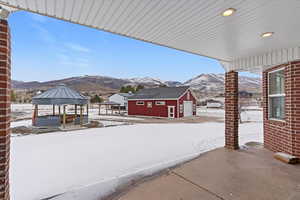 Snow covered patio with a gazebo, an outbuilding, a patio area, and a mountain view