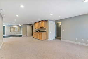 Kitchen featuring open floor plan, recessed lighting, light carpet, light countertops, and light wood finish cabinets