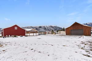 Yard layered in snow featuring an outbuilding, a mountain view, a gazebo, and a garage