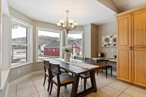 Dining room with a mountain view, light tile patterned flooring, and suspended lighting