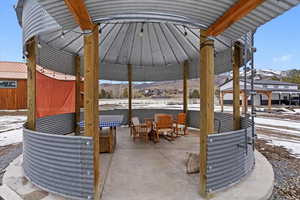 Snow covered patio with a mountain view, a gazebo, and a patio area