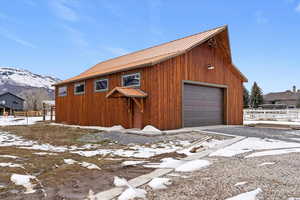 Snow covered garage featuring a detached garage and a mountain view