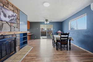 Dining room featuring light wood-style floors, a fireplace, and a ceiling fan
