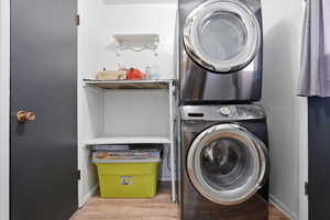 Laundry area with stacked washer and dryer and light wood-style floors