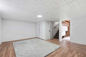 Bonus room featuring light wood-style flooring and wooden walls