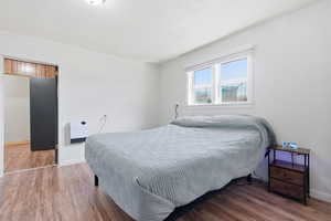 Bedroom with wood finished floors, crown molding, and heating unit