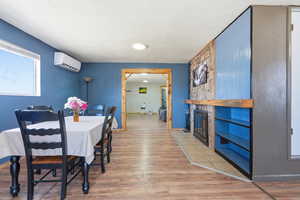 Dining area with light wood-type flooring and a stone fireplace