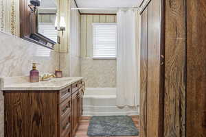 Full bathroom with vanity, shower / bathtub combination with curtain, and light wood-style flooring