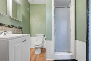 Bathroom featuring vanity, a wainscoted wall, a shower stall, and light wood-style floors