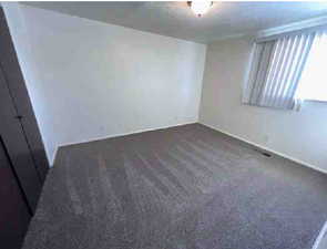 Unfurnished bedroom featuring dark carpet and baseboards