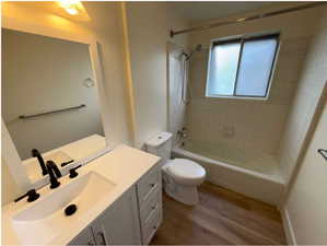 Bathroom with vanity, washtub / shower combination, and dark wood-type flooring
