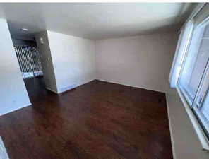 Unfurnished living room featuring dark wood-type flooring