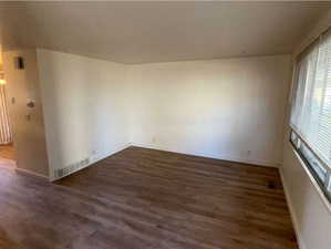 Unfurnished room featuring dark wood-type flooring and baseboards