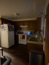 Kitchen featuring white appliances, light countertops, and dark wood finished floors