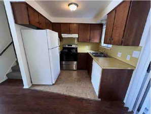 Kitchen with freestanding refrigerator, light countertops, stainless steel range with electric stovetop, and dark wood finish cabinetry