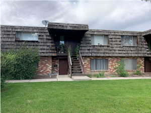 View of front of property featuring mansard roof, a front lawn, and brick siding