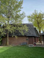 Back of property featuring a lawn and brick siding
