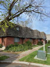 View of front of home featuring mansard roof, brick siding, and a front lawn