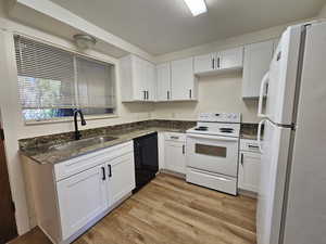 Kitchen with white appliances, dark stone counters, a textured ceiling, white cabinetry, and light wood finished floors