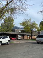 View of front of property featuring mansard roof, covered parking, brick siding, and a mountain view