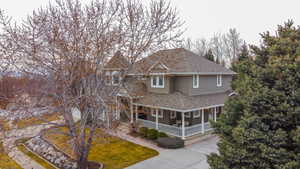 View of front of property with covered porch, a shingled roof, and a front yard