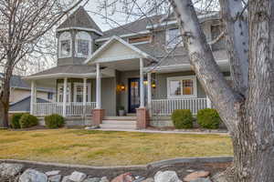 Victorian-style house with a shingled roof, a front yard, and a porch