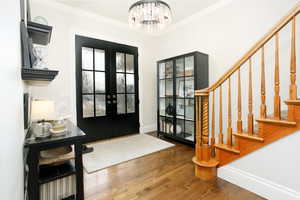 Entrance foyer featuring wood-type flooring, french doors, and hanging lights