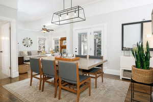 Dining room featuring dark wood-type flooring, a ceiling fan, and crown molding