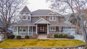 Victorian home with a front lawn, covered porch, and roof with shingles