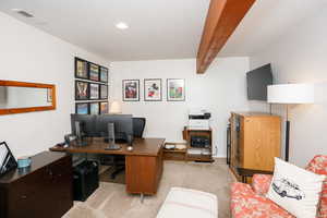 Office space with light colored carpet and beamed ceiling