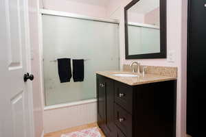 Full bath with a wainscoted wall, vanity, and light wood-style floors